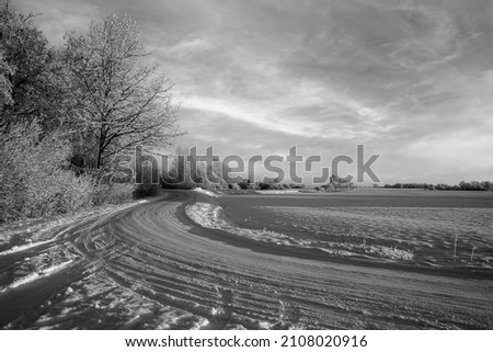 winding snow covered country road, frosty winter morning, white agricultural field