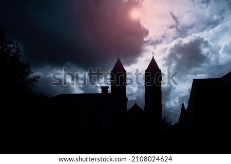 Silhouette of medieval castle and the cathedral church at night over dark sky background with the full moon