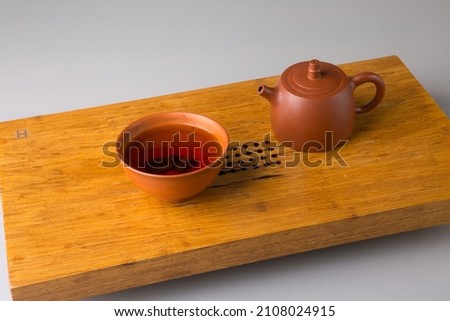 Teapot and cup with freshly brewed pu-erh tea. A set on a wooden table for tea ceremonies.