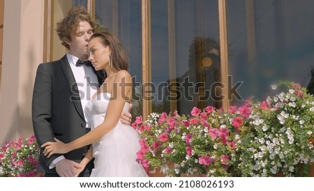 Beautiful newlyweds hug on background of flowers. Action. Beautiful elegant couple of newlyweds embrace on warm sunny day Royalty-Free Stock Photo #2108026193
