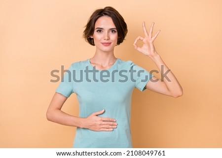 Photo of young lady arm on belly show fingers okey symbol good promo isolated over beige color background Royalty-Free Stock Photo #2108049761