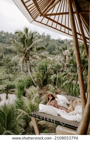 Young woman relaxing in a hotel in Bali, Indonesia, surrounded by jungle, palm trees and rice fields
