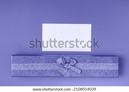 Gift box with tie and card on a very peri background. Holiday gifts closeup with copy space