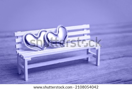 Pair of hearts on a white bench on a very peri background. Love concept, closeup with copy space.