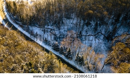 Drone photo of the bend of the road leading through the frosty winter forests and groves covered with the first snow. High quality photo