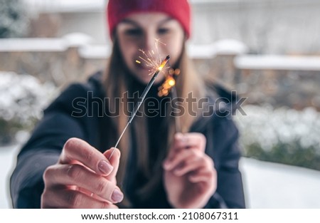 Close-up young woman holding sparklers in her hands.