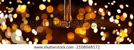 Banner made with transparent serum pipette with drops on dark background with gold light blurred and bokeh. Cosmetics greeting concept. Extreme close up. Royalty-Free Stock Photo #2108068172