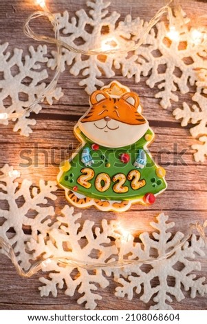 Selective focus of gingerbread tiger 2022. Toy tiger. Tiger 2022 on wood background. Vertical photo. Christmas tree.