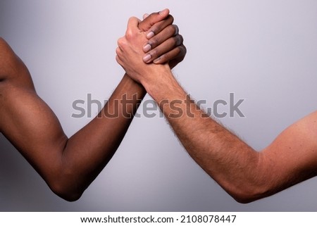 Two arms, one white caucasian and one black african, do arm wrestling, concept of diversity, racism