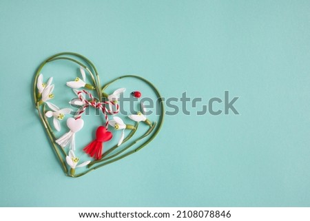 Green and turquoise background with a heart of snowdrops and red and white lace with tassels. Postcard for the holiday on March 1, Martisor, Baba Marta. Royalty-Free Stock Photo #2108078846