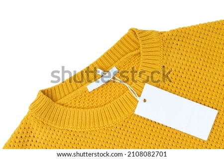 White blank rectangular clothing tag, label mockup template on yellow knitted sweater isolated on white background . Price tag label with copy space for text