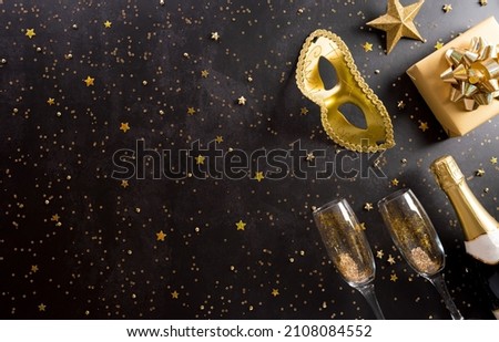 Happy Purim carnival decoration concept made from golden mask, wine, gift box and sparkle star on dark background. (Happy Purim in Hebrew, jewish holiday celebrate) Royalty-Free Stock Photo #2108084552