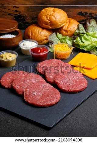 Raw beef burger patties on a black cutting board. Selective focus
