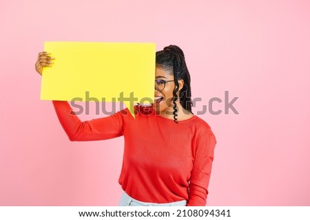 Amazing Offer. Overjoyed girl holding empty speech bubble, pointing finger up, pink studio wall, copyspace
