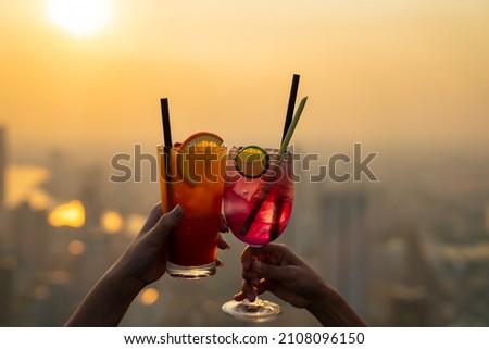 Beautiful Asian woman friends meeting and drinking cocktail together at skyscraper rooftop restaurant in metropolis at summer sunset. Female friend enjoy outdoor lifestyle activity in the city at nigh Royalty-Free Stock Photo #2108096150