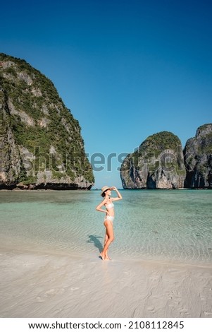 Portrait of asian woman tourist in swimsuit sightseeing and enjoying on the white sand Maya Bay beach and turquoise water, Phi Phi island, Thailand