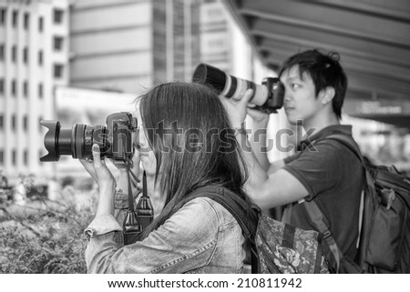 Couple of asian photographers making pictures in city center.