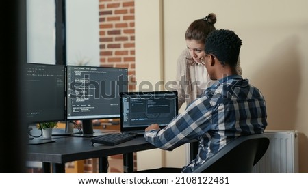 Two programmers doing high five hand gesture at desk with multiple screens running code celebrating successful algorithm. Software developers colleagues enjoying teamwork results in it agency Royalty-Free Stock Photo #2108122481
