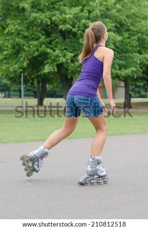 Woman is skating rollerblades in the park.