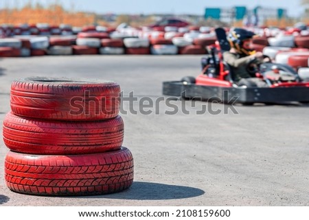 Three car tires are stacked on top of each other on the go-kart track. the boundaries of the sports zone, karting competitions. fun karting Royalty-Free Stock Photo #2108159600
