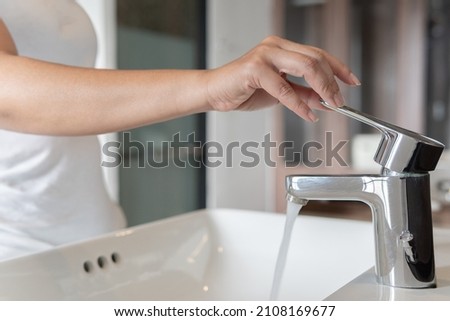 Close up Woman open pull off chrome faucet washbasin to washing hands soap for corona virus at water tap. Faucet and water running drop off. Bathroom interior background with sink basin and tap. Royalty-Free Stock Photo #2108169677