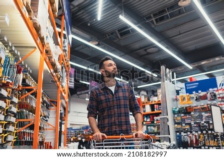 buy a man walking with a basket in a hardware store Royalty-Free Stock Photo #2108182997