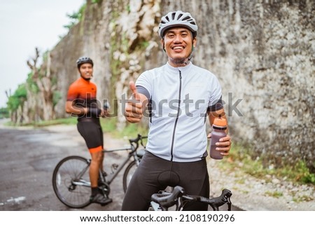 road bike cyclist take a brake and drink a bottle of water Royalty-Free Stock Photo #2108190296