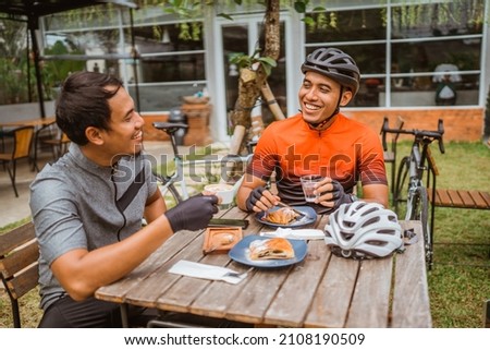 two cyclist enjoying coffee in the cafe after riding Royalty-Free Stock Photo #2108190509