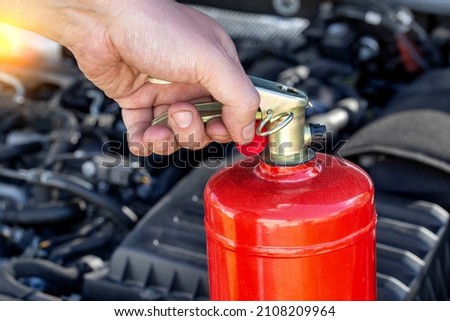 Car fire extinguisher on the background of the car engine. Extinguishing class of fire extinguisher, expiration date.
