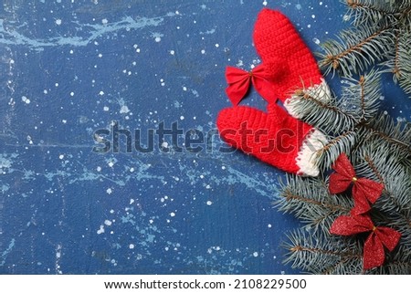 Christmas composition with gloves and fir branches on blue background, closeup