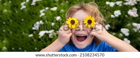 Banner with spring child face. Funny Boy Kid and Daisies. Happy little blond hair child with flowers eyes on the grass with daisies flowers. Child dreaming and smiling against camomile field.