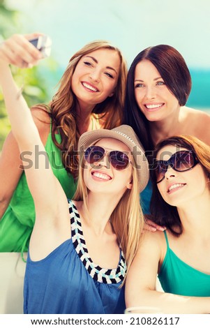 summer holidays and technology - girls taking photo in cafe on the beach