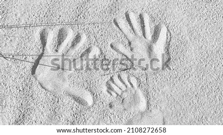 handprints in the sand on the beach of the Baltic Sea in black and white. Connectedness of a family with father, mother and child. Symbol of togetherness for eternity