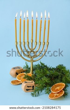 Dreidels, menorah and Christmas decor on color background