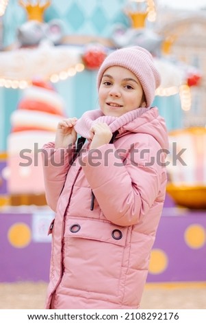 Little happy girl in pink at Christmas fair. People buy gifts for holiday at Christmas market. High quality photo