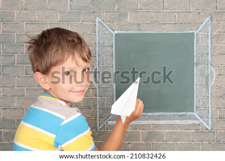 The schoolboy the starting paper plane in the open window drawn on a chalkboard