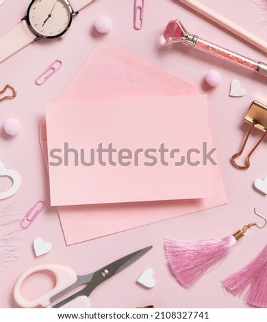 Pink paper card with envelope, school accessories and hearts on pastel pink top view, blank card mockup. Girly workplace. Back to school and valentines day concepts