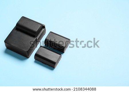 Camera batteries and charger on blue background