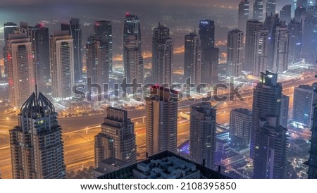 JLT skyscrapers and marina towers near Sheikh Zayed Road aerial night to day transition timelapse. Illuminated residential buildings and skyline with villas. Foggy morning before sunrise