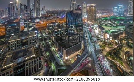 Futuristic Dubai Downtown and finansial district skyline aerial night timelapse. Many illuminated towers and skyscrapers with traffic on streets near shopping mall