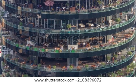 Dubai marina architecture and building with different restaurants at each floor aerial timelapse close up view to people sitting at the tables