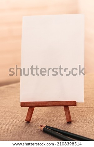 Wooden mini Easel with Blank White Canvas, paper for Artists and Painters - Mockup. Mini Wooden Stand with Clean Artboard on brown background, Copy Space, mock up