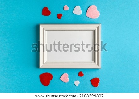 Valentine's Day composition with photo frame and hearts on light blue background. Wedding, birthday, woman's and mother day concept. Flat lay, top view, copy space