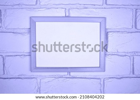 Empty white frame on brick wall background. Template for design in trendy color of 2022.
