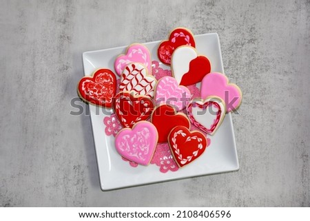 A variety of heart shaped sugar cookies with royal icing on a white plate for Valentines day.