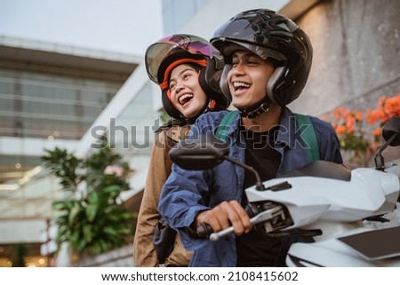 a man and woman laughing while riding a motorcycle Royalty-Free Stock Photo #2108415602