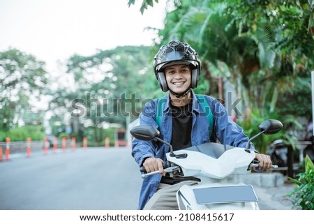 Asian man riding a motorcycle on the street Royalty-Free Stock Photo #2108415617