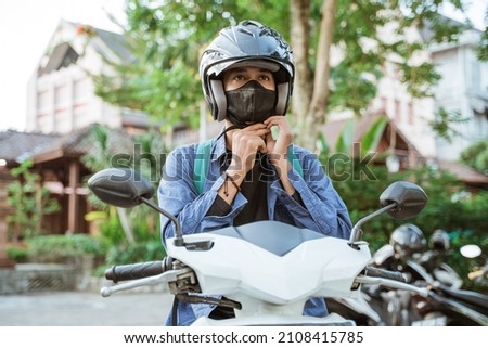 Man getting ready to wear helmet and mask on motorbike Royalty-Free Stock Photo #2108415785