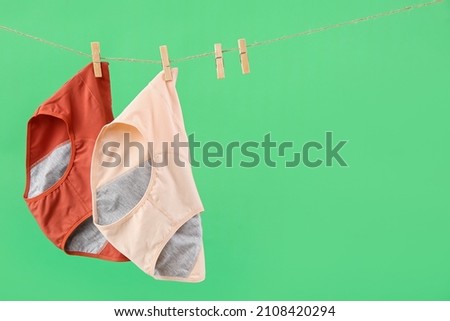 Period panties hanging on rope against green background