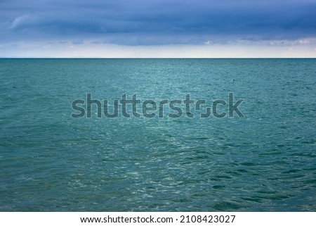 Blue sea in the evening with small waves. Ripples on the surface of the water. Dark blue clouds in the sky. Natural marine landscape.